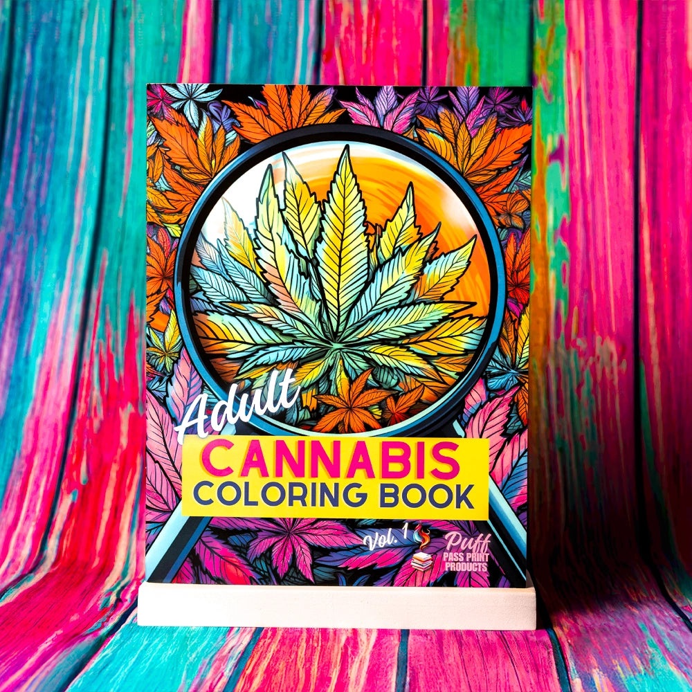 A vibrant and colorful cover of the "Adult Cannabis Coloring Book, Vol. 1" by Puff Pass Print. The cover features an intricate and eye-catching design with a large cannabis leaf surrounded by a pattern of colorful leaves in shades of orange, yellow, blue, and purple. The bold text in white and yellow stands out against the dynamic background, inviting creativity and relaxation.